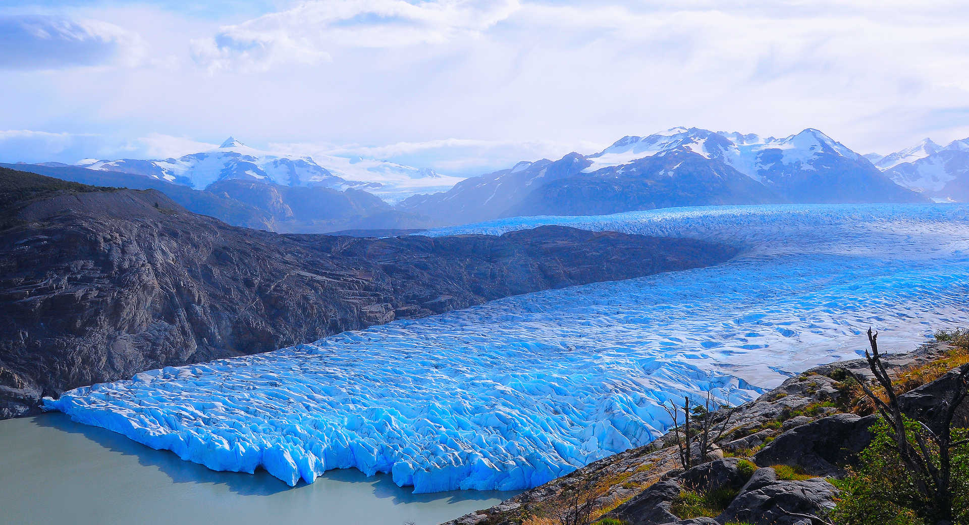 A large blue glacier flowing into a turquoise lake in Patagonia